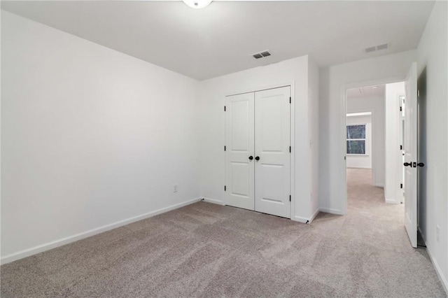 unfurnished bedroom featuring light carpet, visible vents, baseboards, and a closet