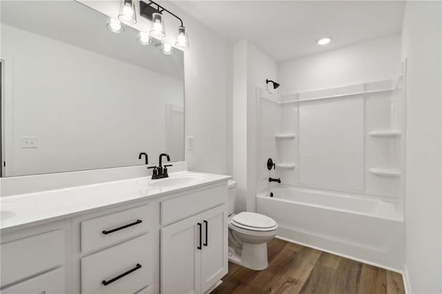 full bath with toilet, double vanity, a sink, and wood finished floors