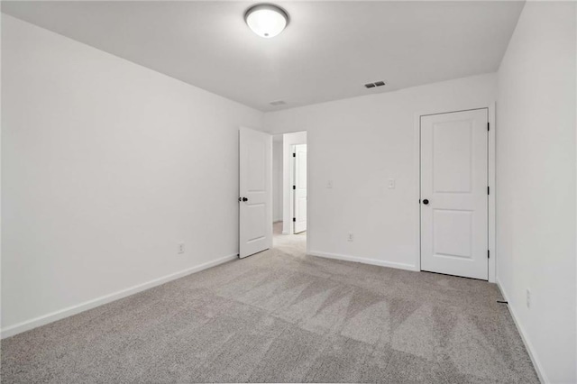 unfurnished room with carpet flooring, visible vents, and baseboards