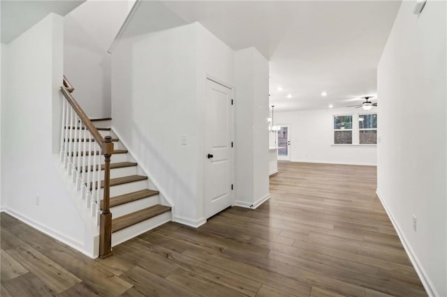 staircase with ceiling fan with notable chandelier, recessed lighting, baseboards, and wood finished floors