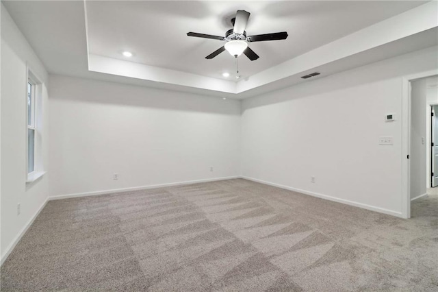 spare room with carpet floors, recessed lighting, a raised ceiling, and baseboards