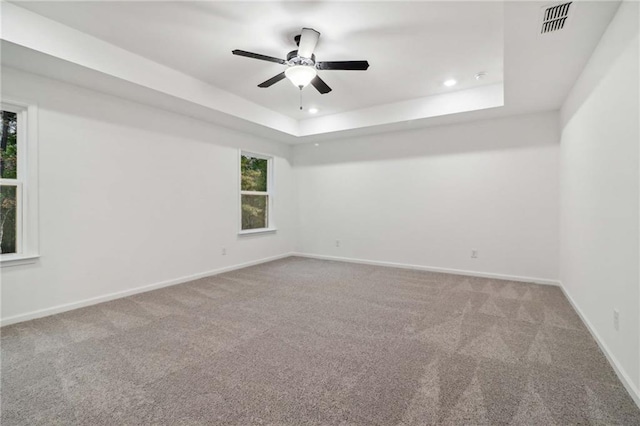 unfurnished room featuring ceiling fan, recessed lighting, baseboards, a tray ceiling, and carpet