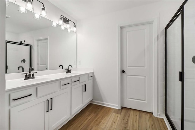 bathroom featuring a stall shower, double vanity, a sink, and wood finished floors