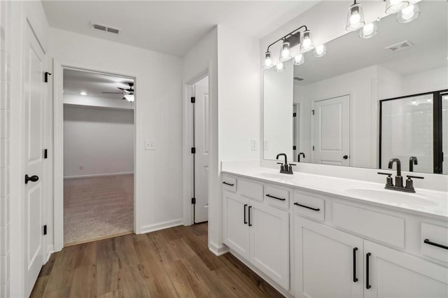 full bath with a stall shower, visible vents, a sink, and wood finished floors