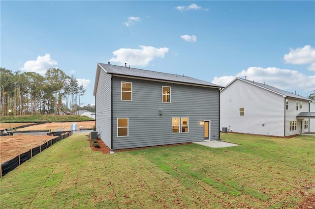 rear view of property featuring a yard, fence, and central AC unit