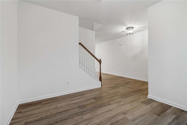 empty room featuring stairs, baseboards, and wood finished floors