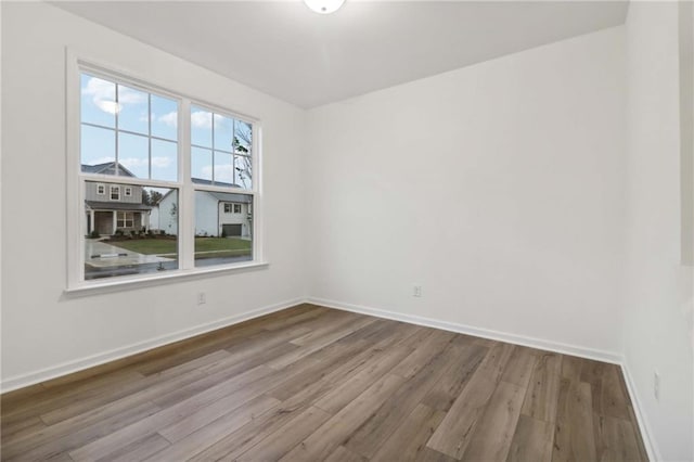 spare room with baseboards and wood finished floors