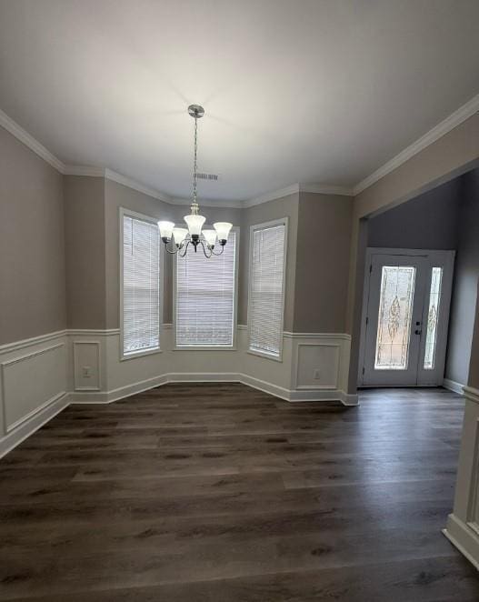 unfurnished dining area with a chandelier, dark wood-style floors, and crown molding