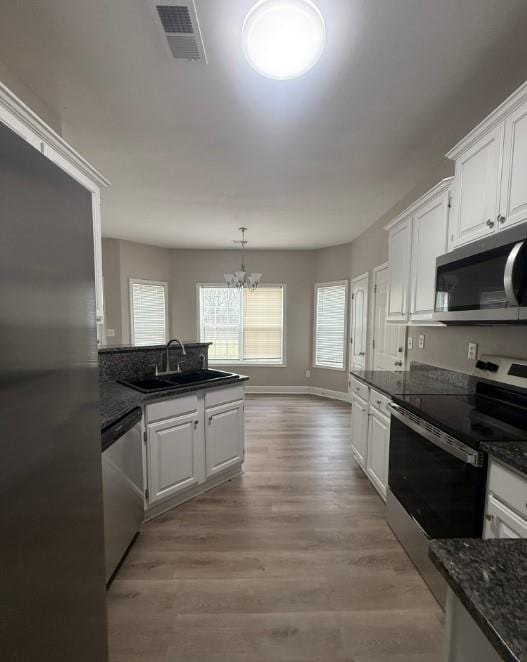 kitchen featuring visible vents, stainless steel appliances, a notable chandelier, white cabinetry, and a sink