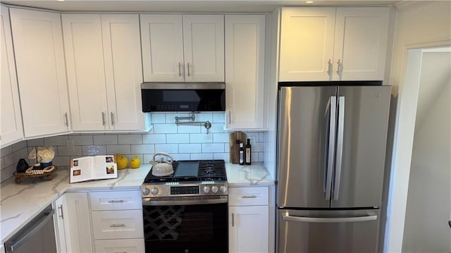 kitchen featuring white cabinetry, light stone counters, backsplash, and stainless steel appliances