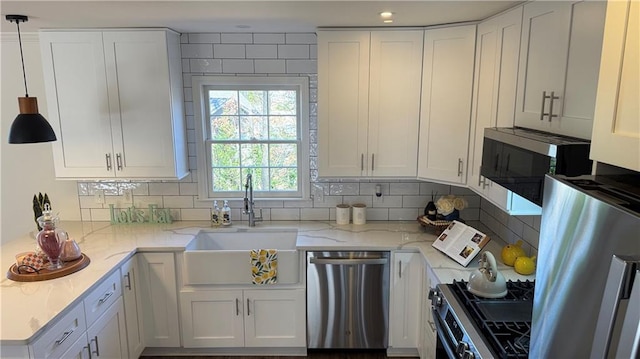 kitchen featuring light stone countertops, tasteful backsplash, appliances with stainless steel finishes, and a sink