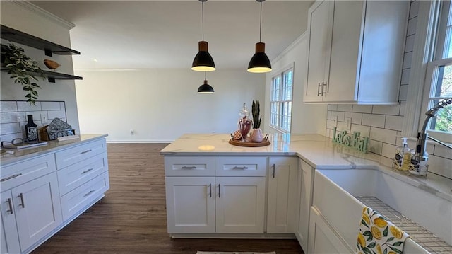 kitchen with dark wood-style floors, a peninsula, ornamental molding, a sink, and tasteful backsplash