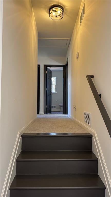 stairway featuring baseboards and visible vents