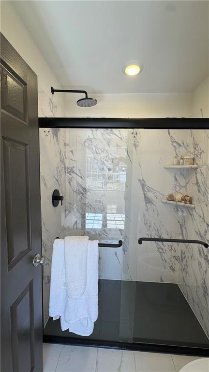 bathroom with a marble finish shower and marble finish floor