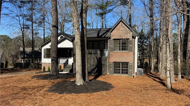 view of front facade featuring brick siding, central AC, and a chimney