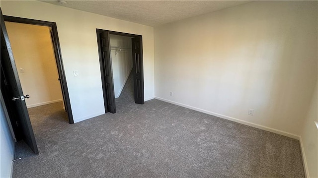 unfurnished bedroom with a closet, baseboards, dark carpet, and a textured ceiling