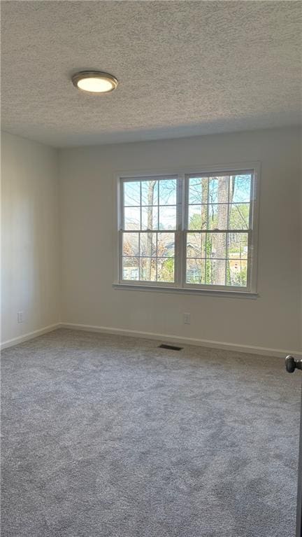 empty room featuring visible vents, baseboards, a textured ceiling, and carpet flooring