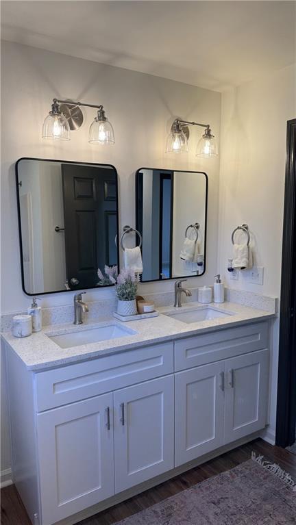 full bath with double vanity, wood finished floors, and a sink