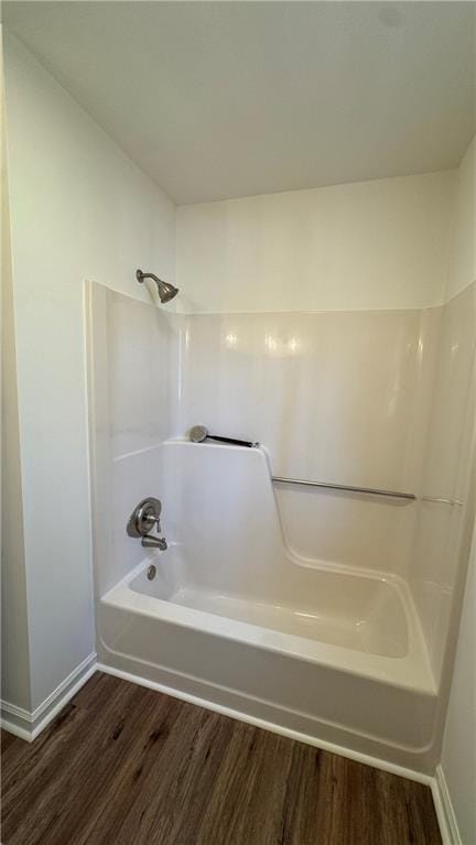 full bath featuring baseboards, shower / washtub combination, and wood finished floors