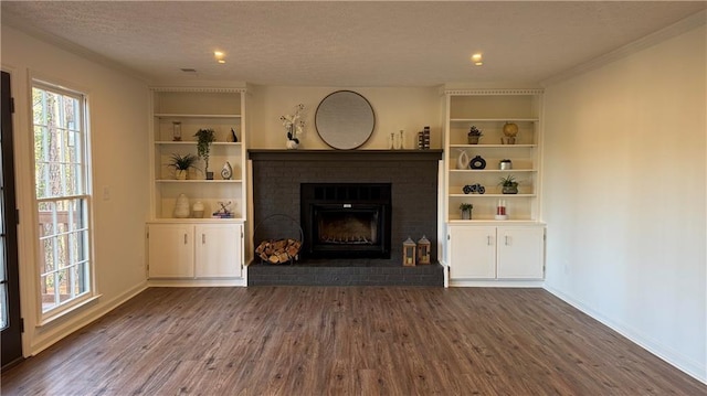 unfurnished living room with a brick fireplace, a textured ceiling, dark wood-type flooring, and baseboards