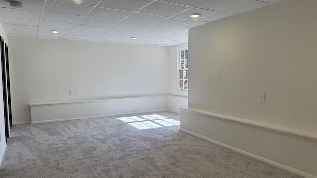 carpeted spare room with baseboards and a drop ceiling