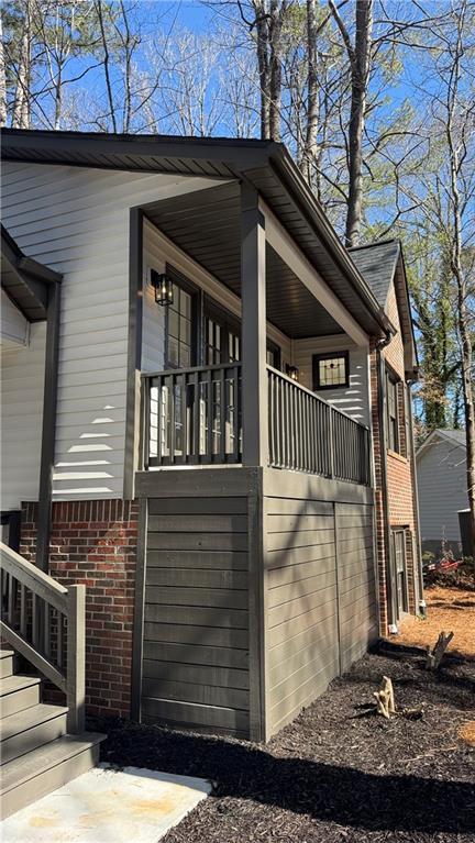 view of side of home featuring brick siding and covered porch