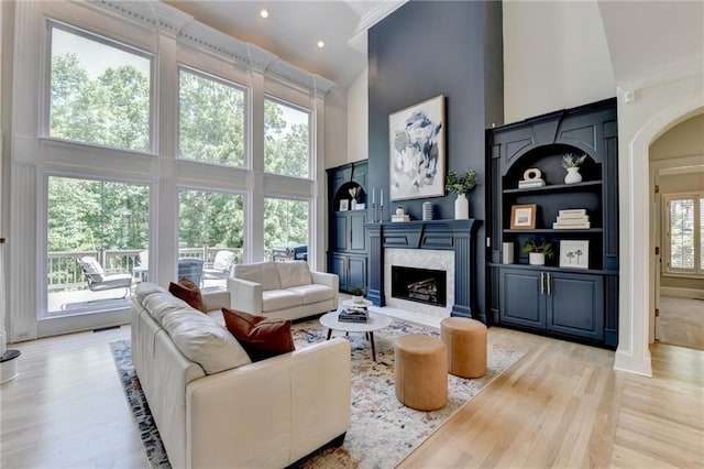 7920 Tintern Trce, Duluth, GA 30097 - living area with a towering ceiling, a fireplace, light wood-style flooring, arched walkways, and recessed lighting