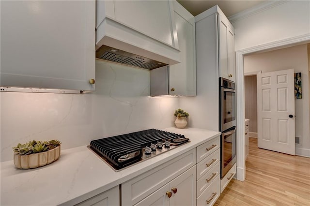 7920 Tintern Trce, Duluth, GA 30097 - kitchen with stainless steel appliances, light countertops, light wood-style flooring, white cabinetry, and crown molding