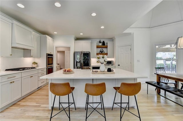 7920 Tintern Trce, Duluth, GA 30097 - kitchen with stainless steel appliances, open shelves, light wood-style flooring, a kitchen island, and a breakfast bar