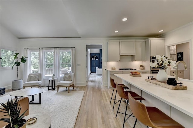 7920 Tintern Trce, Duluth, GA 30097 - kitchen with a breakfast bar area, light wood-style floors, black cooktop, recessed lighting, and baseboards