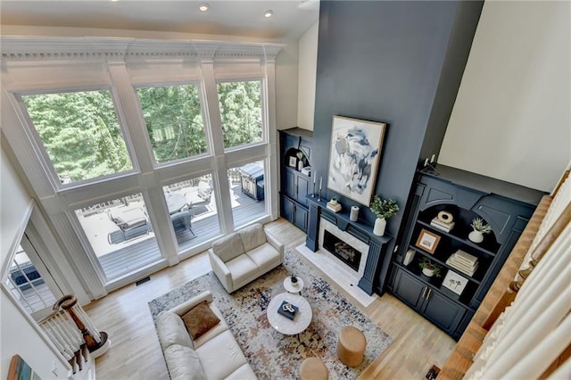7920 Tintern Trce, Duluth, GA 30097 - living area featuring healthy amount of natural light, a fireplace with flush hearth, light wood-style flooring, recessed lighting, and a towering ceiling