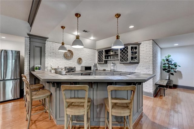 7920 Tintern Trce, Duluth, GA 30097 - kitchen with appliances with stainless steel finishes, a breakfast bar, gray cabinets, light wood-style flooring, and decorative backsplash