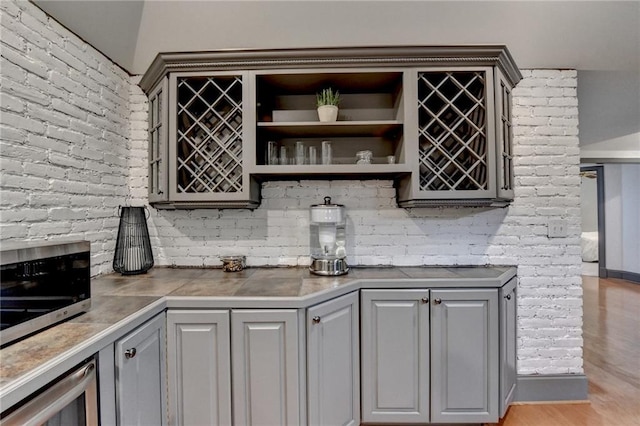 7920 Tintern Trce, Duluth, GA 30097 - kitchen with gray cabinets, stainless steel microwave, open shelves, beverage cooler, and light wood finished floors
