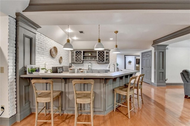 7920 Tintern Trce, Duluth, GA 30097 - kitchen with light wood-style flooring, gray cabinetry, a kitchen bar, and a peninsula