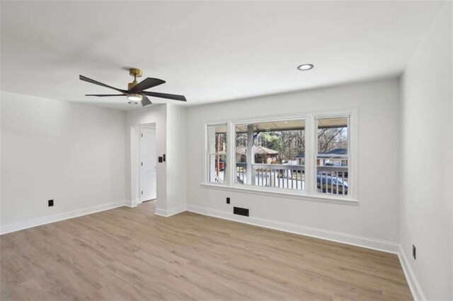 spare room with a ceiling fan, light wood-type flooring, visible vents, and baseboards