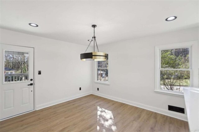 unfurnished dining area featuring recessed lighting, visible vents, baseboards, and wood finished floors