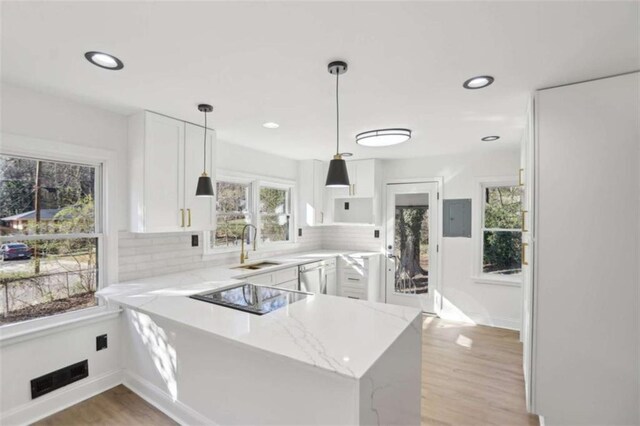 kitchen featuring light stone counters, black electric stovetop, stainless steel dishwasher, white cabinetry, and a peninsula