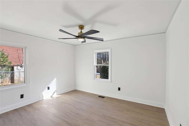 empty room featuring visible vents, ceiling fan, baseboards, and wood finished floors