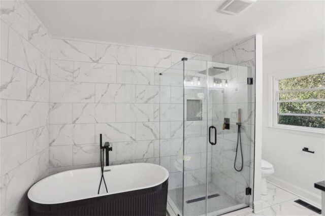 bathroom featuring marble finish floor, a freestanding tub, visible vents, and a shower stall