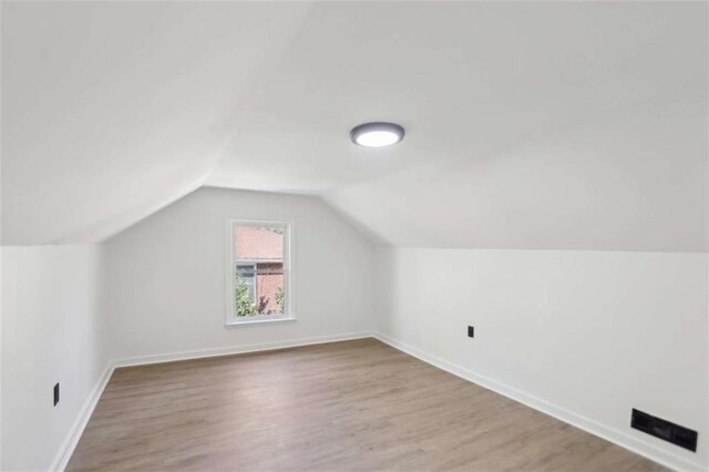 additional living space featuring vaulted ceiling, visible vents, light wood-style flooring, and baseboards