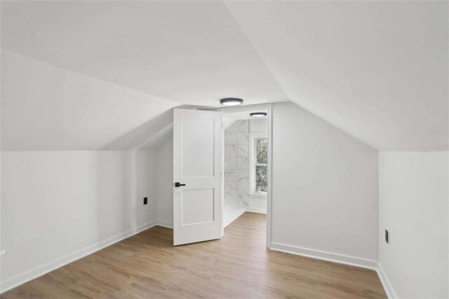 bonus room with lofted ceiling, light wood-style floors, and baseboards