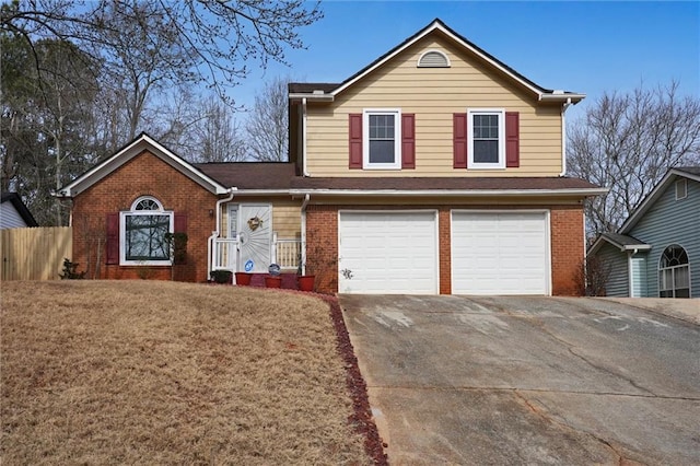 view of front facade with a front yard, fence, an attached garage, concrete driveway, and brick siding