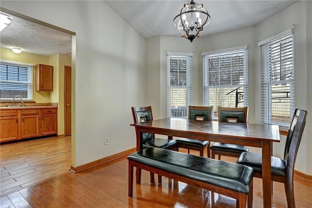 dining space with sink, light hardwood / wood-style flooring, a chandelier, and plenty of natural light