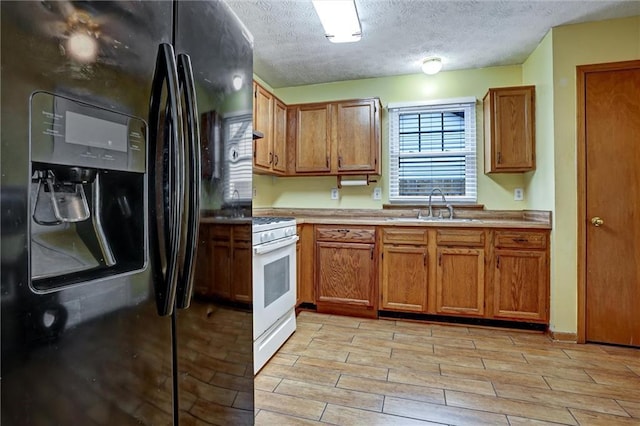 kitchen featuring white gas range, black refrigerator with ice dispenser, sink, and a textured ceiling