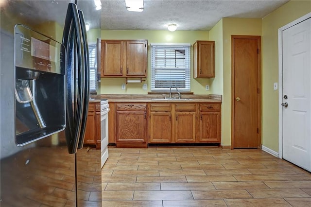 kitchen featuring white range, black fridge with ice dispenser, sink, and a textured ceiling