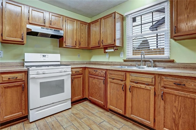 kitchen featuring white range with gas cooktop, sink, a textured ceiling, and light wood-type flooring