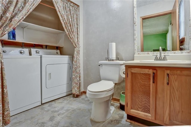 bathroom featuring washing machine and clothes dryer, vanity, and toilet