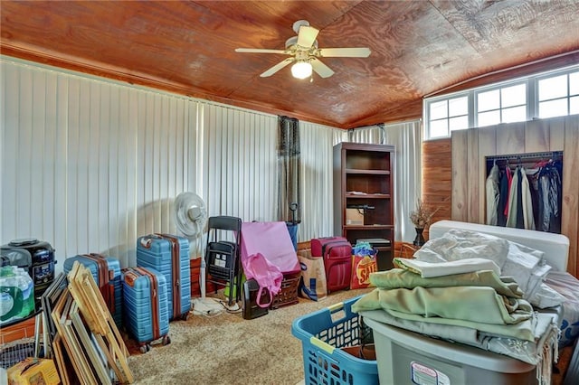 interior space featuring lofted ceiling, wooden walls, ceiling fan, and carpet flooring