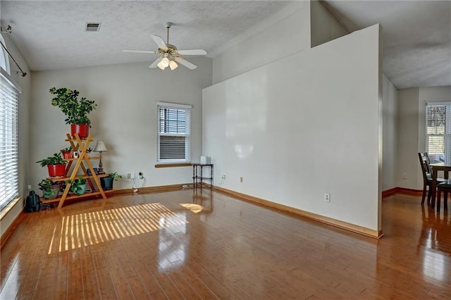 exercise area with hardwood / wood-style flooring, a healthy amount of sunlight, lofted ceiling, and a textured ceiling