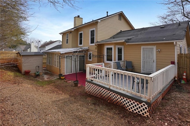 back of property featuring a wooden deck and a storage unit